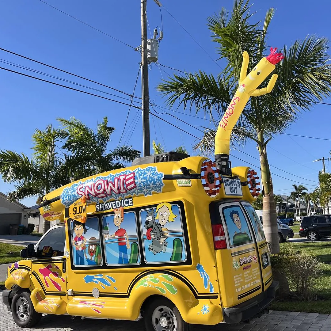The bus with Bob, the inflatable mascot, under palm trees