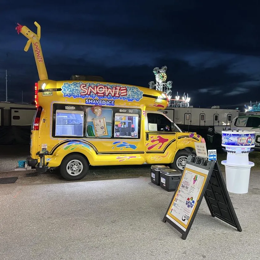The bus lit up at night at a fair, with Bob and the Flavor Station