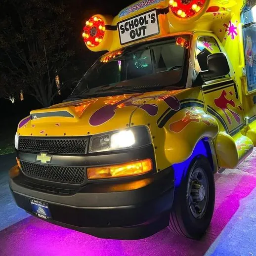 The front of the bus at night with purple underglow and glowing roof speakers