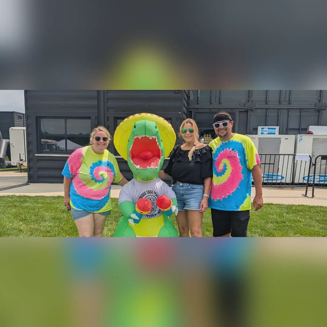 The team in tie-dye Snowie shirts with an inflatable dinosaur at Columbus Taco Fest