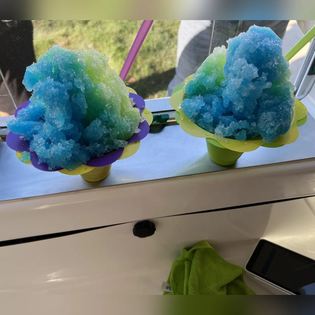 Two blue and green shaved ice in Flower Cups on the serving window ledge