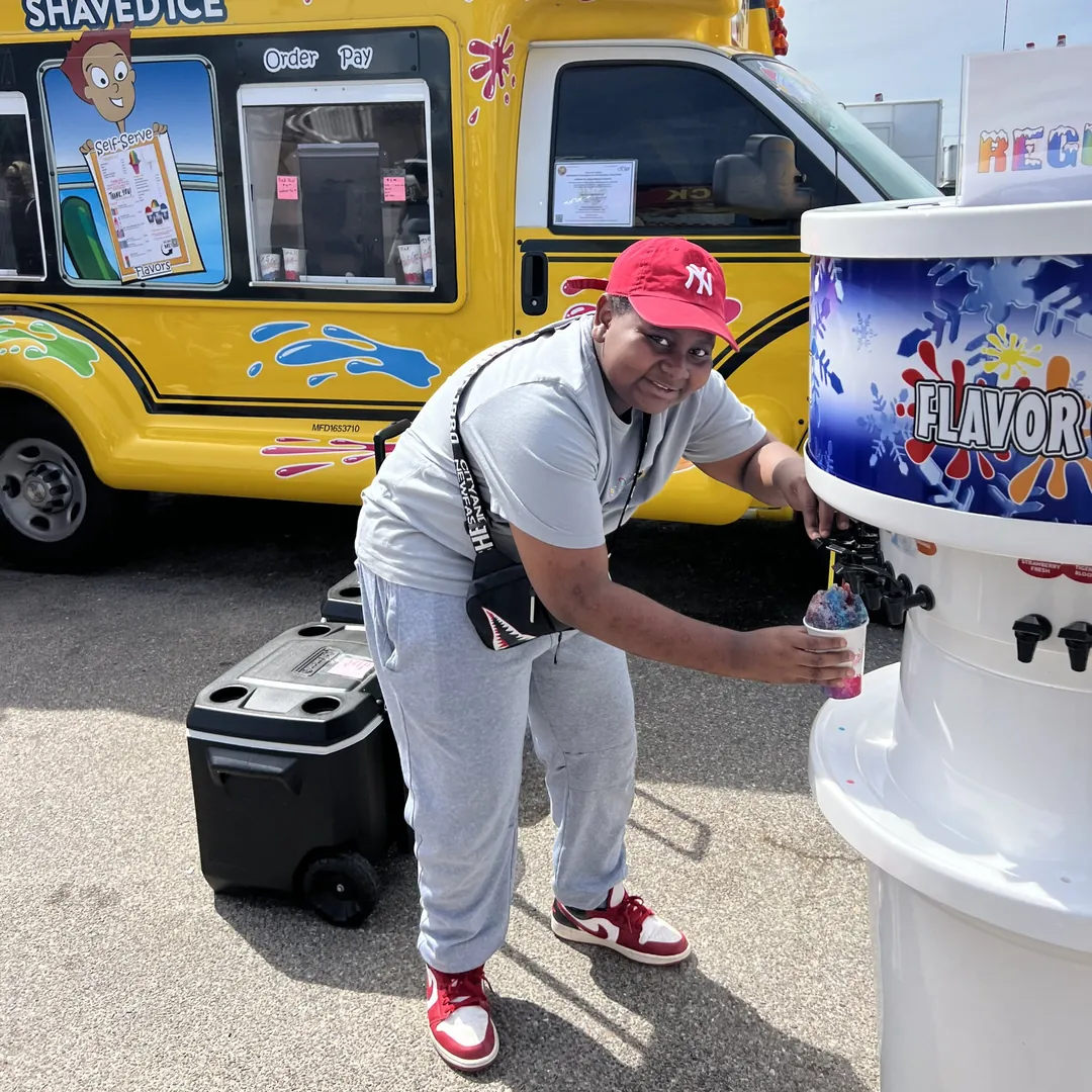 A young guest pouring syrup at the self-serve Flavor Station next to the bus