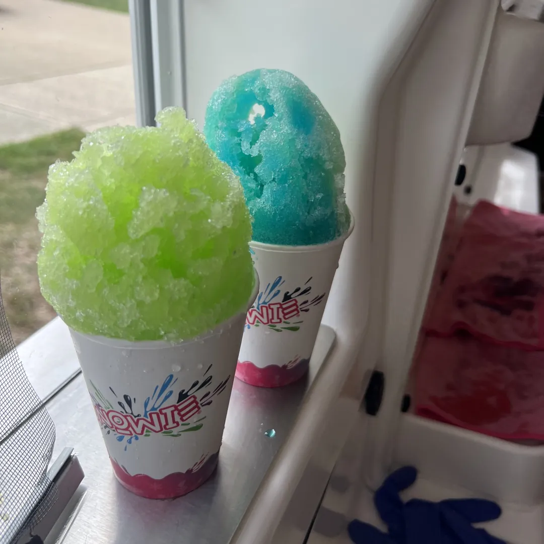 A green and a blue Snowie Shaved Ice on the serving window ledge